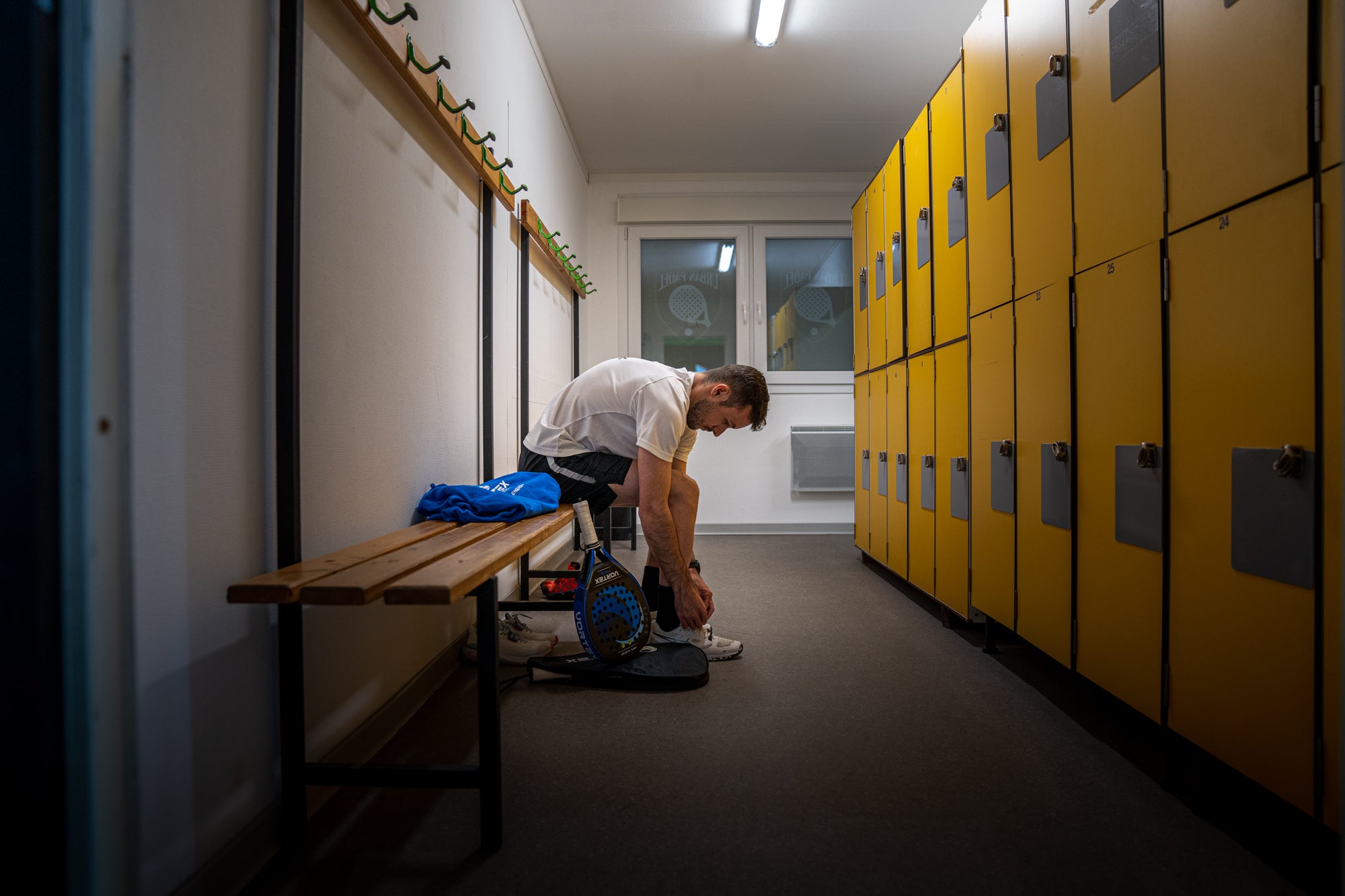 Photo d'un joueur dans les vestiaires entrain de se préparer pour rentrer sur le terrain avec sa raquette VRTX Master